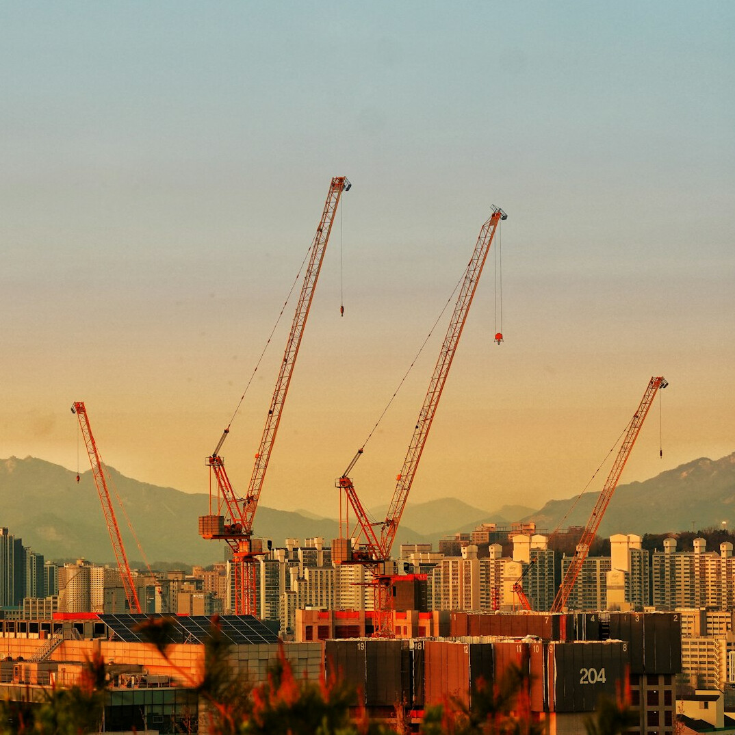 Construction cranes against a changing city skyline